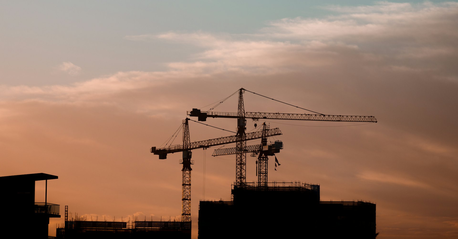 Tower cranes working over a construction site at sunset
